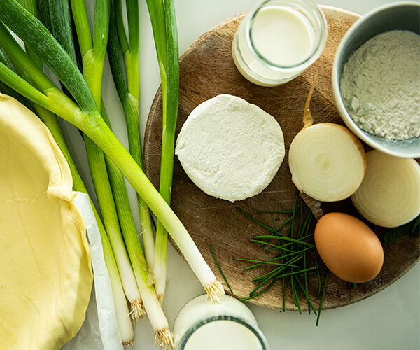 Ingrédients de la recette de quiche à la ciboule. pâte, farine, oignon doux, crème, lait, oeuf, fromage de chèvre, oignon ciboule